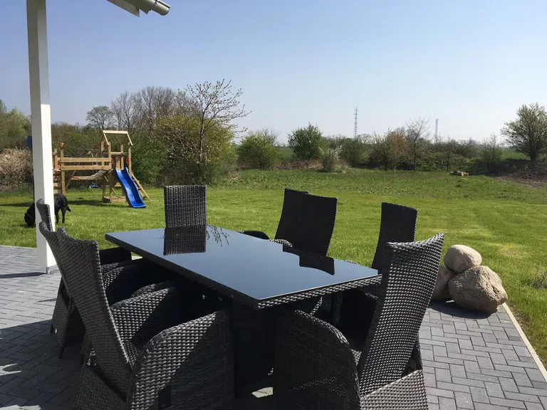 Überdachte Terrasse mit Gartenmöbeln und Blick auf den Spielplatz