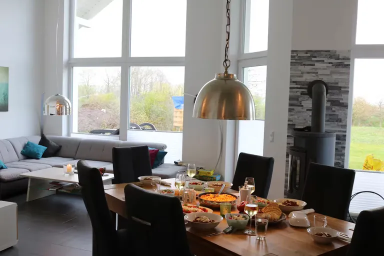 Esszimmer mit gedecktem Tisch und großen Fenstern zum Garten