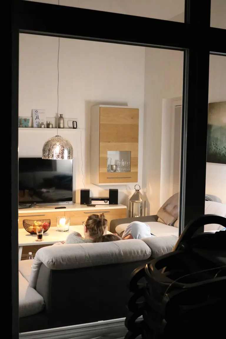 Blick durch die Glasfront ins gemütliche Wohnzimmer bei Nacht